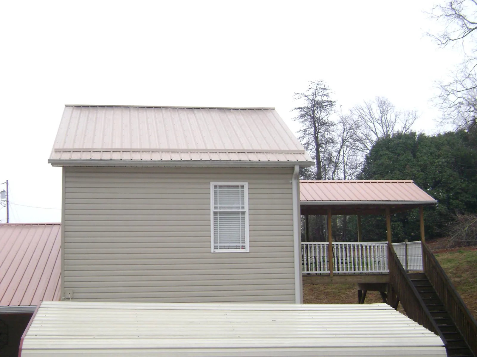 Tan metal roofs on a two story addition and attached porch, from a Roof Replacement job in Montville