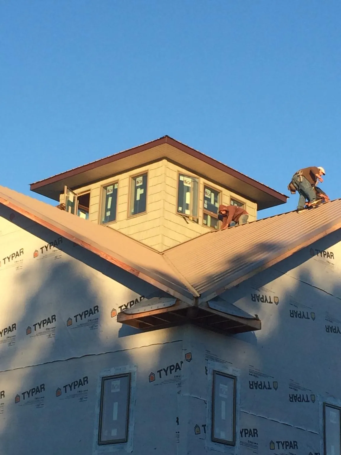 Roofers working around a rooftop cupola on a new metal roof at sunset — Roof Waterproofing in Montville by Roofing Brothers